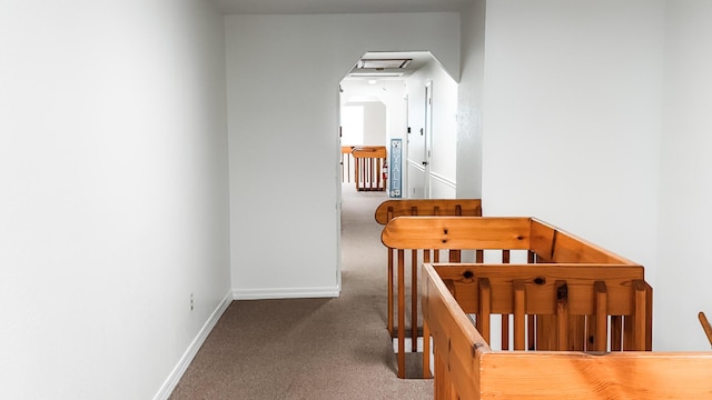 hallway featuring carpet floors, an upstairs landing, and baseboards