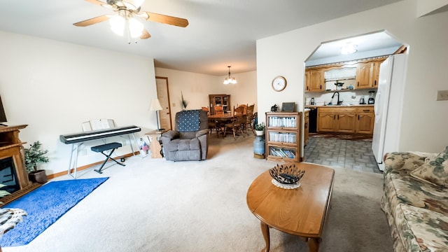 living room with ceiling fan with notable chandelier and light colored carpet