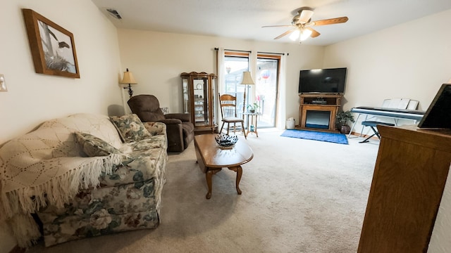 carpeted living area featuring a fireplace, visible vents, and a ceiling fan