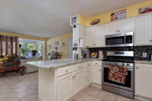 kitchen featuring decorative backsplash, kitchen peninsula, light tile patterned flooring, and appliances with stainless steel finishes