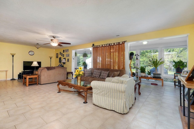 living room featuring a textured ceiling, light tile patterned floors, and ceiling fan