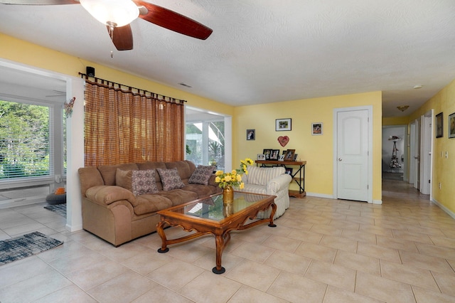 tiled living room with ceiling fan, a textured ceiling, and a healthy amount of sunlight