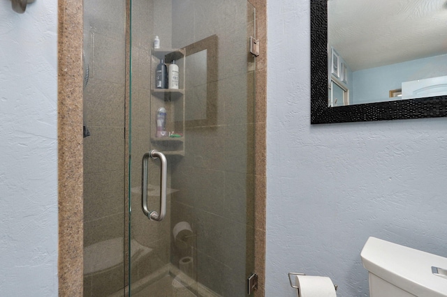 bathroom featuring a textured ceiling, toilet, and an enclosed shower