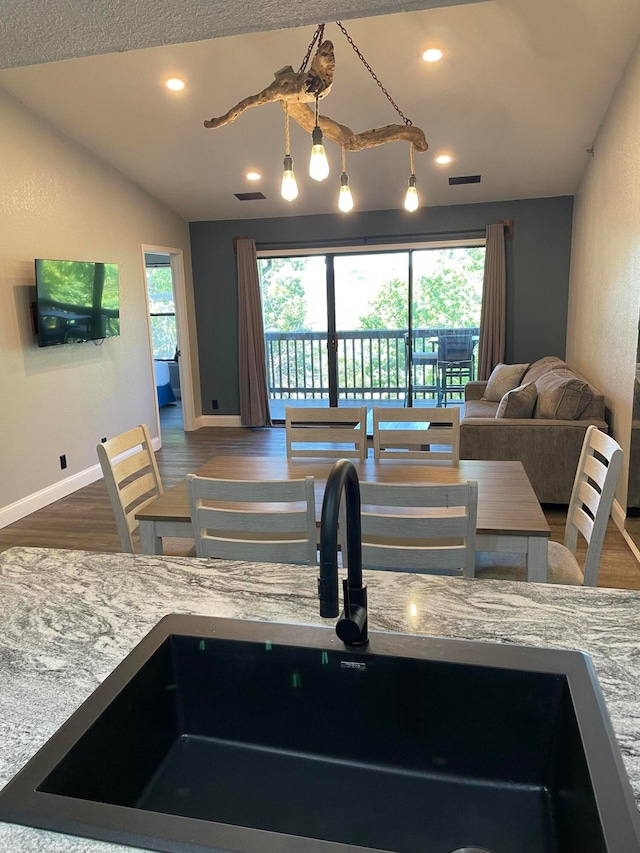 kitchen featuring wood-type flooring, light stone countertops, vaulted ceiling, and sink