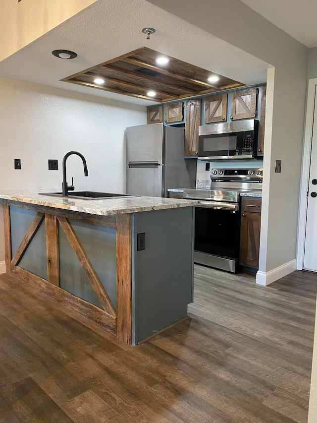 kitchen featuring a tray ceiling, sink, dark hardwood / wood-style floors, appliances with stainless steel finishes, and a textured ceiling