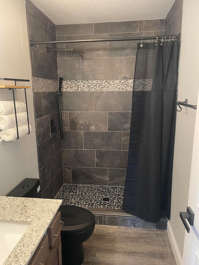 bathroom featuring toilet, hardwood / wood-style floors, a shower with shower curtain, vanity, and a textured ceiling