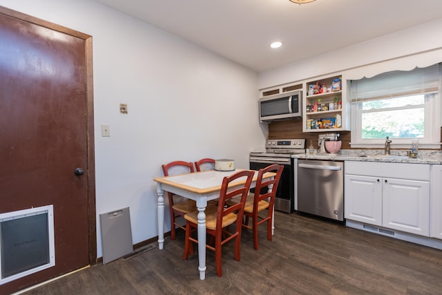 kitchen featuring appliances with stainless steel finishes, dark hardwood / wood-style floors, sink, and white cabinetry