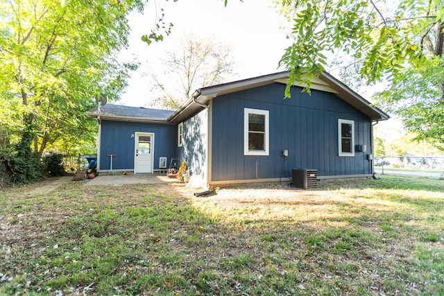 back of property with central AC unit, a lawn, and a patio