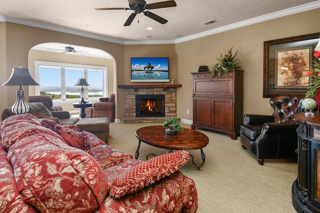 living room with carpet floors, ceiling fan, a fireplace, ornamental molding, and a textured ceiling