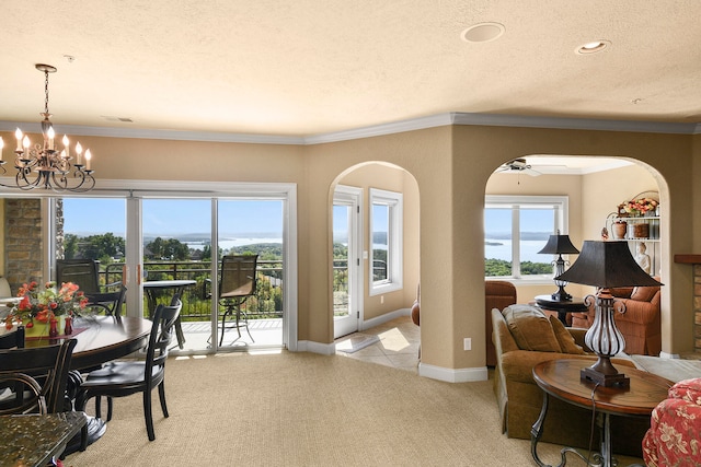 carpeted dining space featuring ceiling fan with notable chandelier, ornamental molding, and a textured ceiling