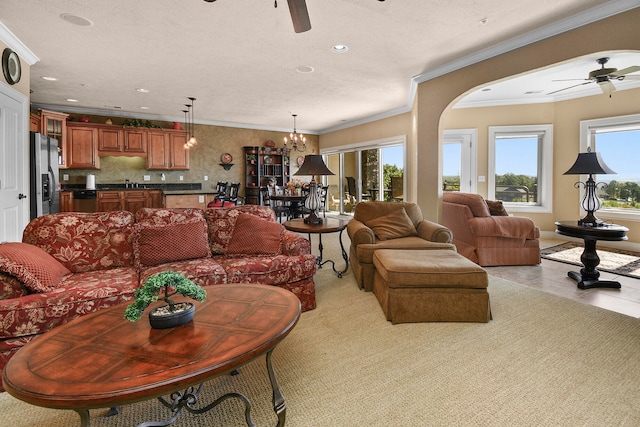 living room with sink, ceiling fan with notable chandelier, ornamental molding, and a textured ceiling