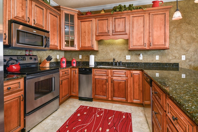 kitchen with dark stone countertops, pendant lighting, appliances with stainless steel finishes, and sink