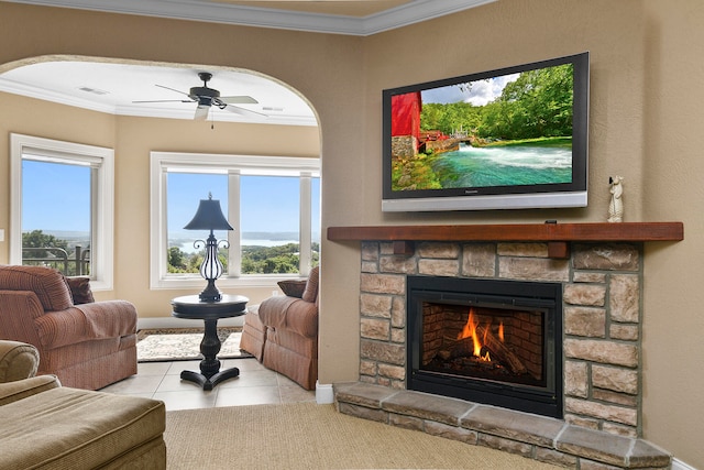 living room featuring crown molding, ceiling fan, a fireplace, and light tile patterned floors