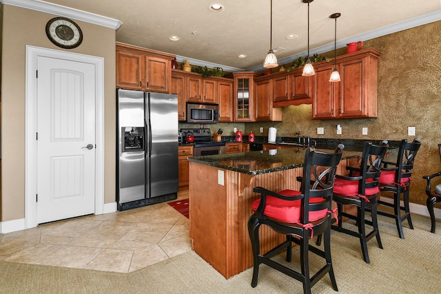 kitchen with pendant lighting, a kitchen island, a kitchen breakfast bar, stainless steel appliances, and ornamental molding