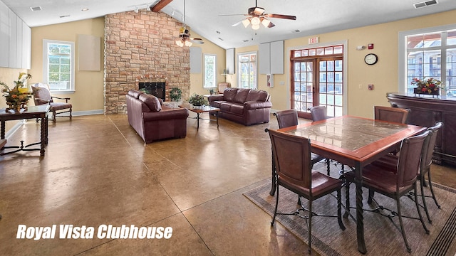 dining room featuring ceiling fan, beamed ceiling, french doors, concrete flooring, and a fireplace