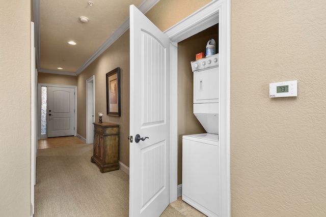 clothes washing area featuring light carpet, stacked washer / dryer, and ornamental molding