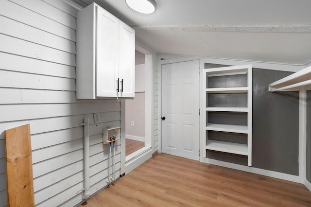 walk in closet with light wood-type flooring and vaulted ceiling