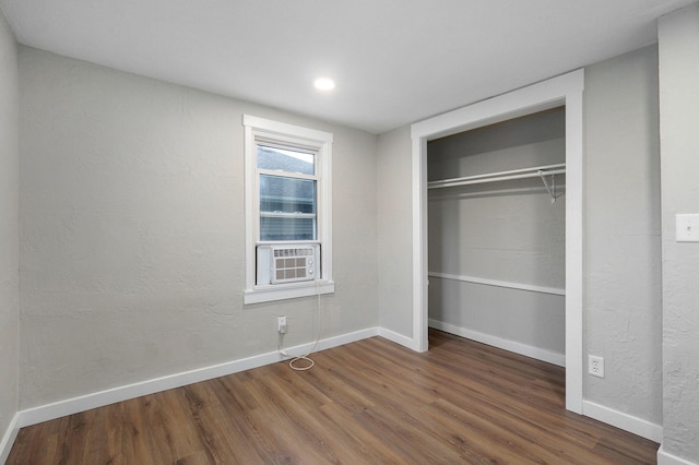 unfurnished bedroom featuring cooling unit, a closet, and dark hardwood / wood-style floors