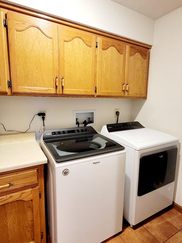 laundry area with light tile patterned flooring, washing machine and clothes dryer, and cabinets