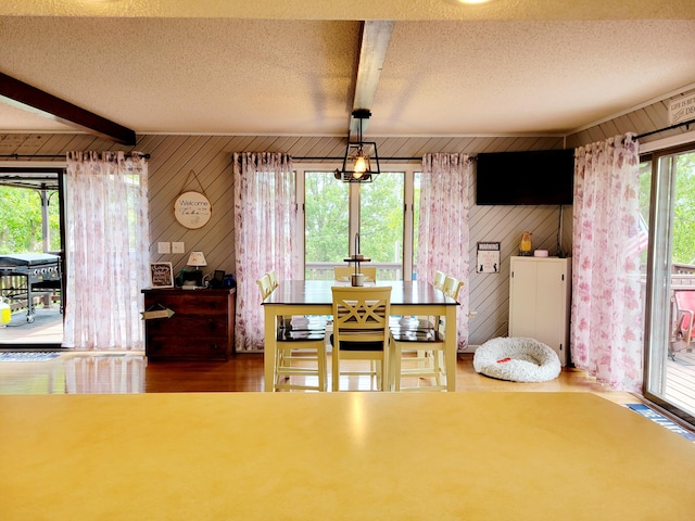 dining area with beamed ceiling, wood-type flooring, and wooden walls