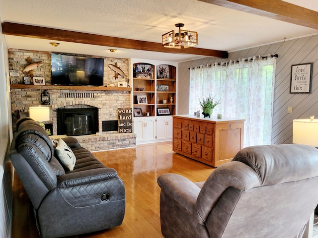 living room featuring a fireplace, beam ceiling, wooden walls, light wood-type flooring, and a textured ceiling