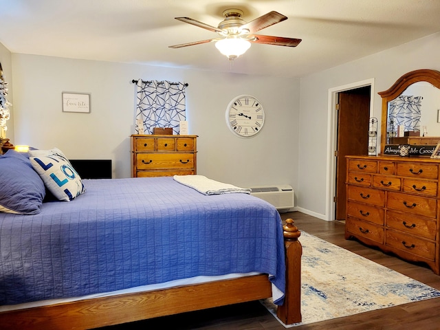 bedroom featuring dark hardwood / wood-style flooring, a wall mounted air conditioner, and ceiling fan