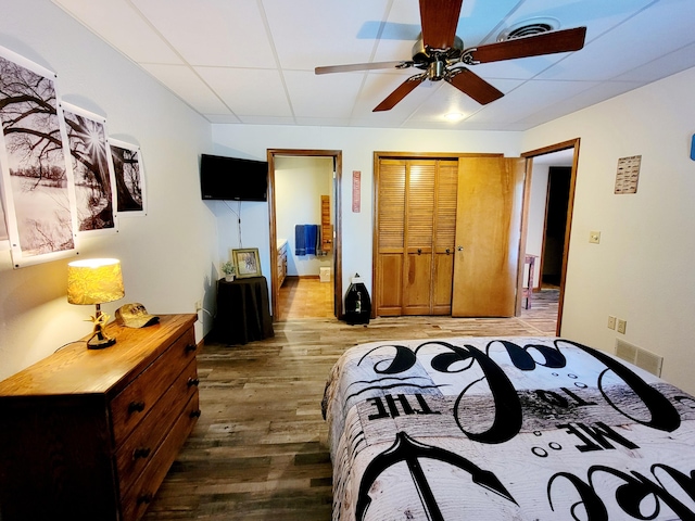 bedroom with a drop ceiling, hardwood / wood-style floors, and ceiling fan