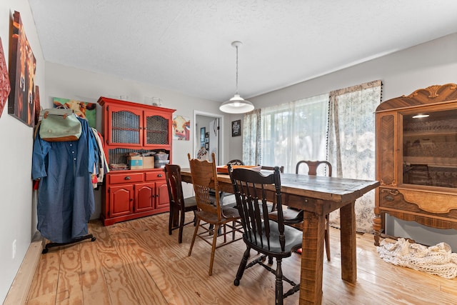 dining area featuring a textured ceiling and light wood-type flooring