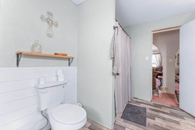 bathroom with wood-type flooring, walk in shower, and toilet