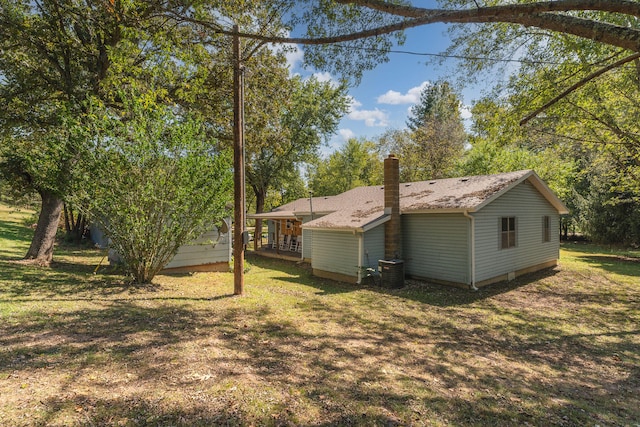 rear view of property with central air condition unit and a yard