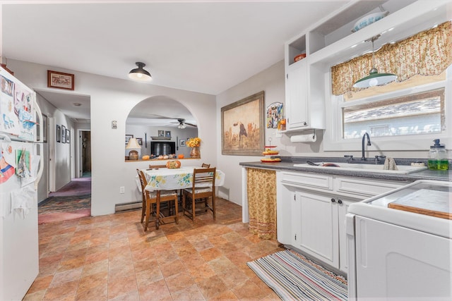 kitchen featuring dark countertops, a sink, ceiling fan, range, and white cabinets