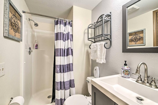 bathroom featuring a shower with curtain, vanity, a textured ceiling, and toilet