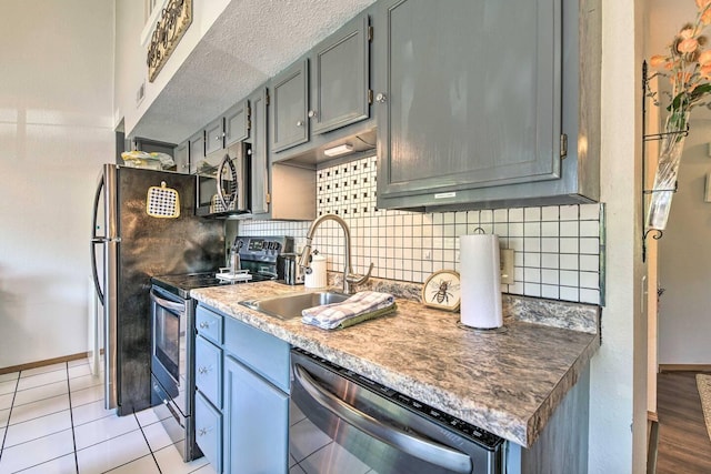 kitchen with gray cabinetry, tasteful backsplash, light hardwood / wood-style flooring, sink, and appliances with stainless steel finishes