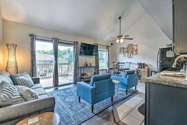 living room with ceiling fan, sink, light tile patterned floors, and high vaulted ceiling