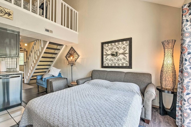 bedroom featuring a towering ceiling and hardwood / wood-style floors