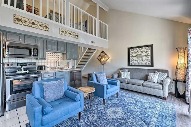 living room with light hardwood / wood-style flooring, a high ceiling, and sink