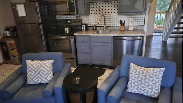 kitchen featuring gray cabinets, tasteful backsplash, wood-type flooring, sink, and appliances with stainless steel finishes