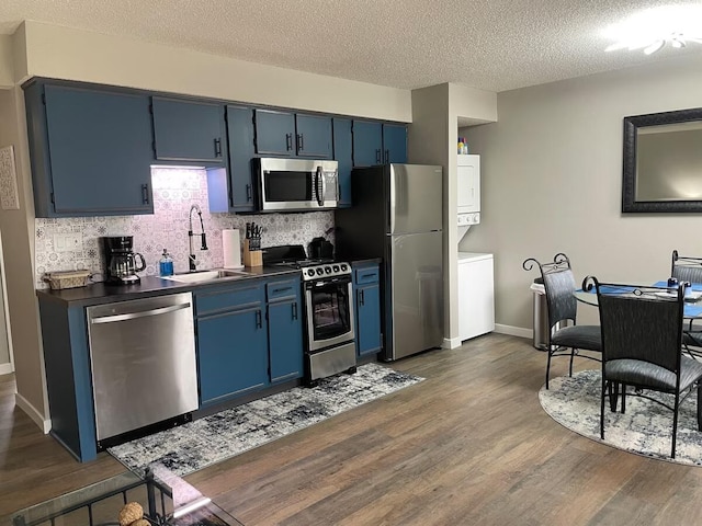 16 Fall Creek Trl Unit 2, Branson, MO 65616 - kitchen with appliances with stainless steel finishes, stacked washing machine and dryer, blue cabinetry, dark wood-style flooring, and a textured ceiling