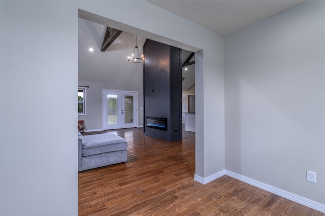 hall featuring beam ceiling, dark wood-type flooring, french doors, and an inviting chandelier