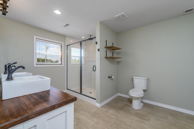 bathroom featuring tile patterned flooring, a shower with shower door, vanity, and toilet