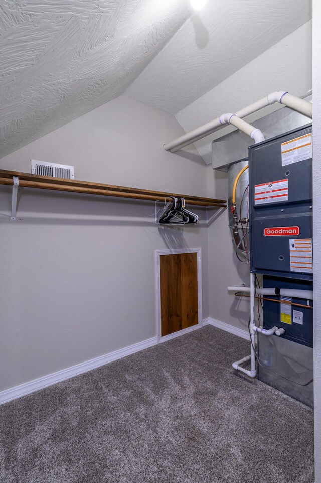 walk in closet with lofted ceiling, heating unit, and carpet flooring