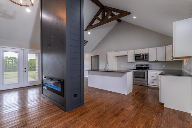 kitchen with dark wood-type flooring, high vaulted ceiling, white cabinetry, stainless steel appliances, and a center island