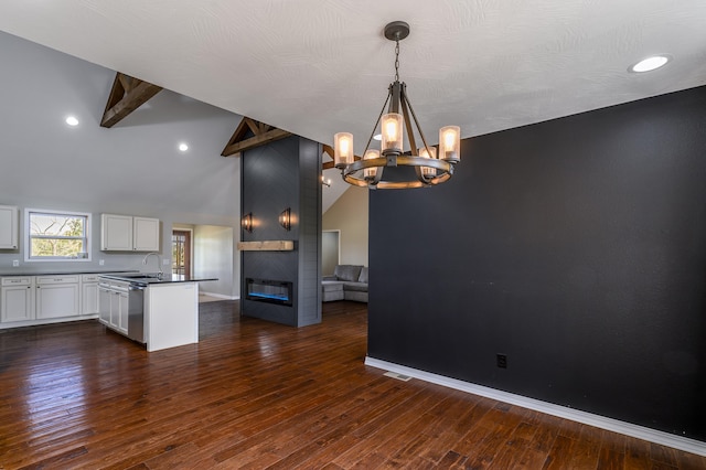 kitchen with white cabinets, stainless steel dishwasher, decorative light fixtures, lofted ceiling with beams, and dark hardwood / wood-style floors