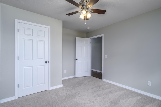 unfurnished bedroom featuring ceiling fan, a textured ceiling, and light carpet