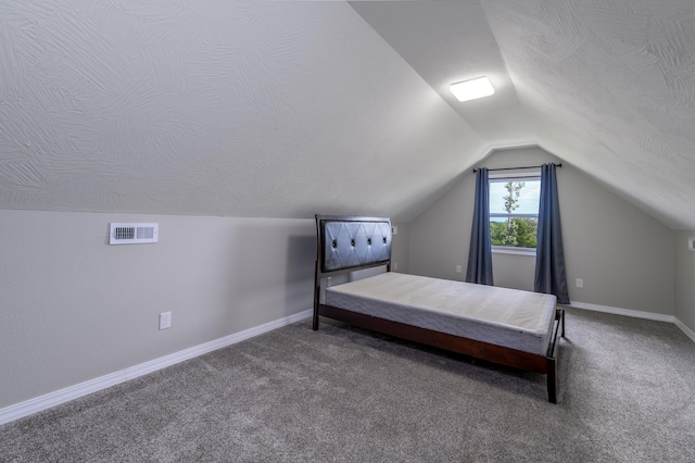 unfurnished bedroom featuring dark colored carpet, a textured ceiling, and vaulted ceiling