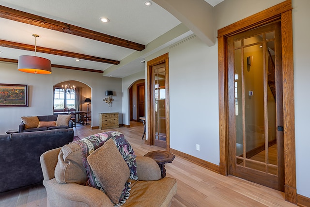 living room with beamed ceiling, a notable chandelier, and light hardwood / wood-style floors