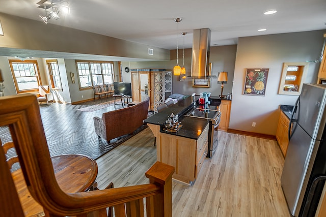 kitchen with light wood-type flooring, exhaust hood, decorative light fixtures, appliances with stainless steel finishes, and a center island