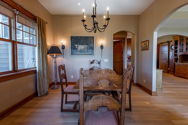 dining space with light hardwood / wood-style floors and a chandelier