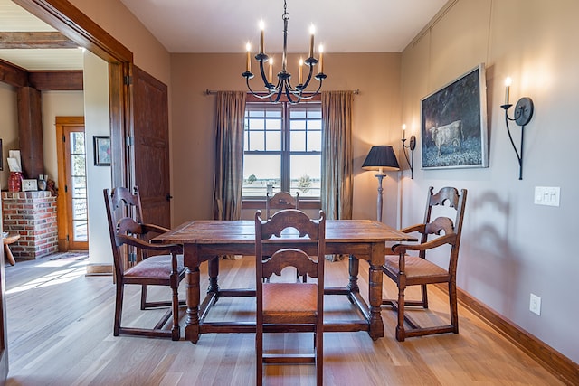 dining area featuring beamed ceiling, an inviting chandelier, and light hardwood / wood-style flooring