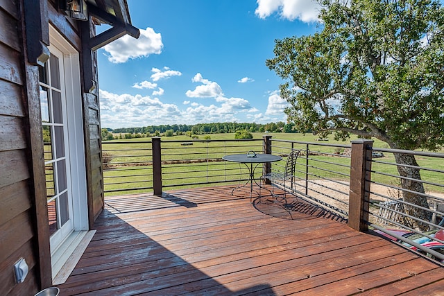 wooden deck featuring a rural view and a lawn